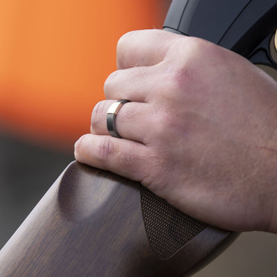 The Gunmetal 5mm Barrel Band with a rose gold insert holding a shotgun.