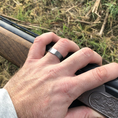 The Gunmetal 5mm Barrel Band with a white gold insert holding a shotgun.