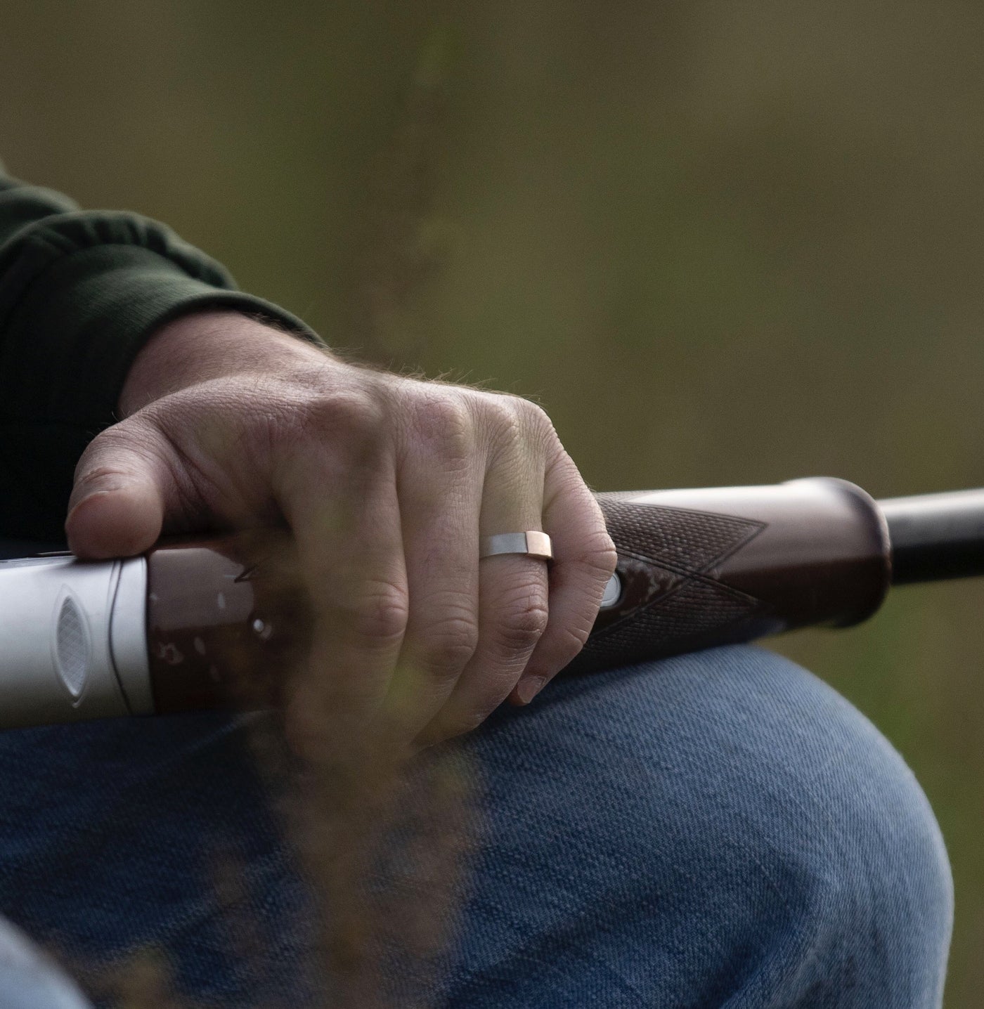 The Classic 5mm Barrel Band with a rose gold insert holding a shotgun.